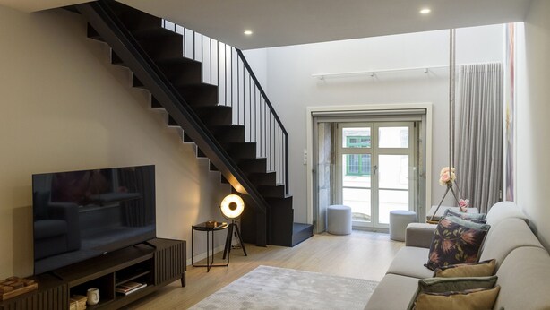 A modern living room with a staircase, a flat-screen TV, a floor lamp, and a sofa with cushions. - RA - S o Jo o 3 in Oporto (Porto)