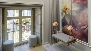 A room with a large window, a view of buildings outside, a grey sofa, a grey rug, and a hanging chair with flowers. - RA - S o Jo o 3 in Oporto (Porto)
