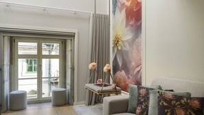 A living room with a grey sofa, two ottomans, a hanging plant, and a large floral artwork on the wall. - RA - S o Jo o 3 in Oporto (Porto)