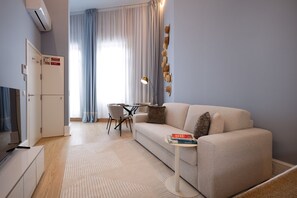 A modern living room with a sofa, a small table with books, a dining area with chairs, and a cabinet. - RA - Flores 1 in Oporto (Porto)