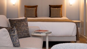 Une chambre d’hôtel avec un lit, des tables de chevet et une petite table sur laquelle se trouvent une assiette et un livre.