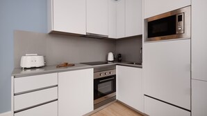 Une cuisine moderne avec des armoires blanches, un four en acier inoxydable, un four à micro-ondes et un grille-pain.