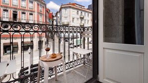Un balcon avec une table et des chaises, un verre à vin et une vue sur les bâtiments.