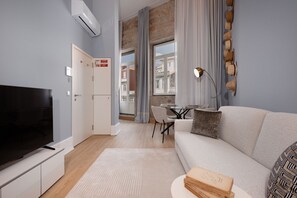 A modern living room with a flat-screen TV, a sofa, a dining table with chairs, and a large window with curtains. - RA - Flores 1 in Oporto (Porto)