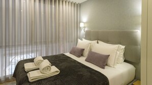 Ett hotellrum med en stor säng, en sänggavel, en sänglampa och ett fönster med gardiner.