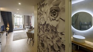 En modern inredning med en stor väggmålning med blommönster, en rund spegel och en matplats med utsikt över en balkong.