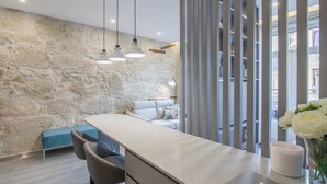 A modern kitchen with a stone wall, bar seating, and a view through a window. - RA - Baixa in Oporto (Porto)