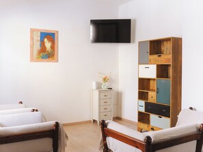 A room with two beds, a TV, a painting, and a wooden cabinet with multiple compartments. - Cascall Marì - Two Bedroom Apartment, Sleeps 4 (Alghero)