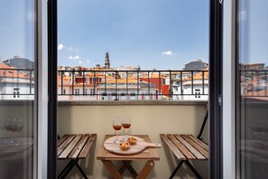 A balcony with a wooden table, two glasses of wine, and a small pastry on a wooden board. - RA - Flores 4 in Oporto (Porto)
