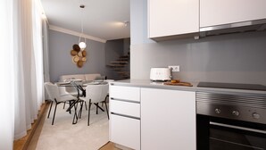 A modern kitchen with white cabinets, a built-in oven, and a dining area with a table and chairs. - RA - Flores 4 in Oporto (Porto)