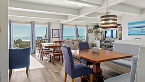 A spacious dining area with a wooden table and blue upholstered chairs, overlooking a scenic view. - Beachfront Aptos Home - Right on the Sand! (Aptos)