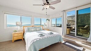 A bedroom with a bed, nightstands, a ceiling fan, and large windows offering ocean views. - Beachfront Aptos Home - Right on the Sand! (Aptos)
