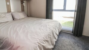 Ein Schlafzimmer mit einem Bett, einem Fenster mit Vorhängen und einer Deckenleuchte.