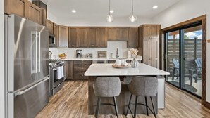 Una cocina moderna con gabinetes de madera, electrodomésticos de acero inoxidable y una isla grande con taburetes de bar.