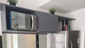 Una cocina moderna con microondas, refrigerador de acero inoxidable y armarios de madera.