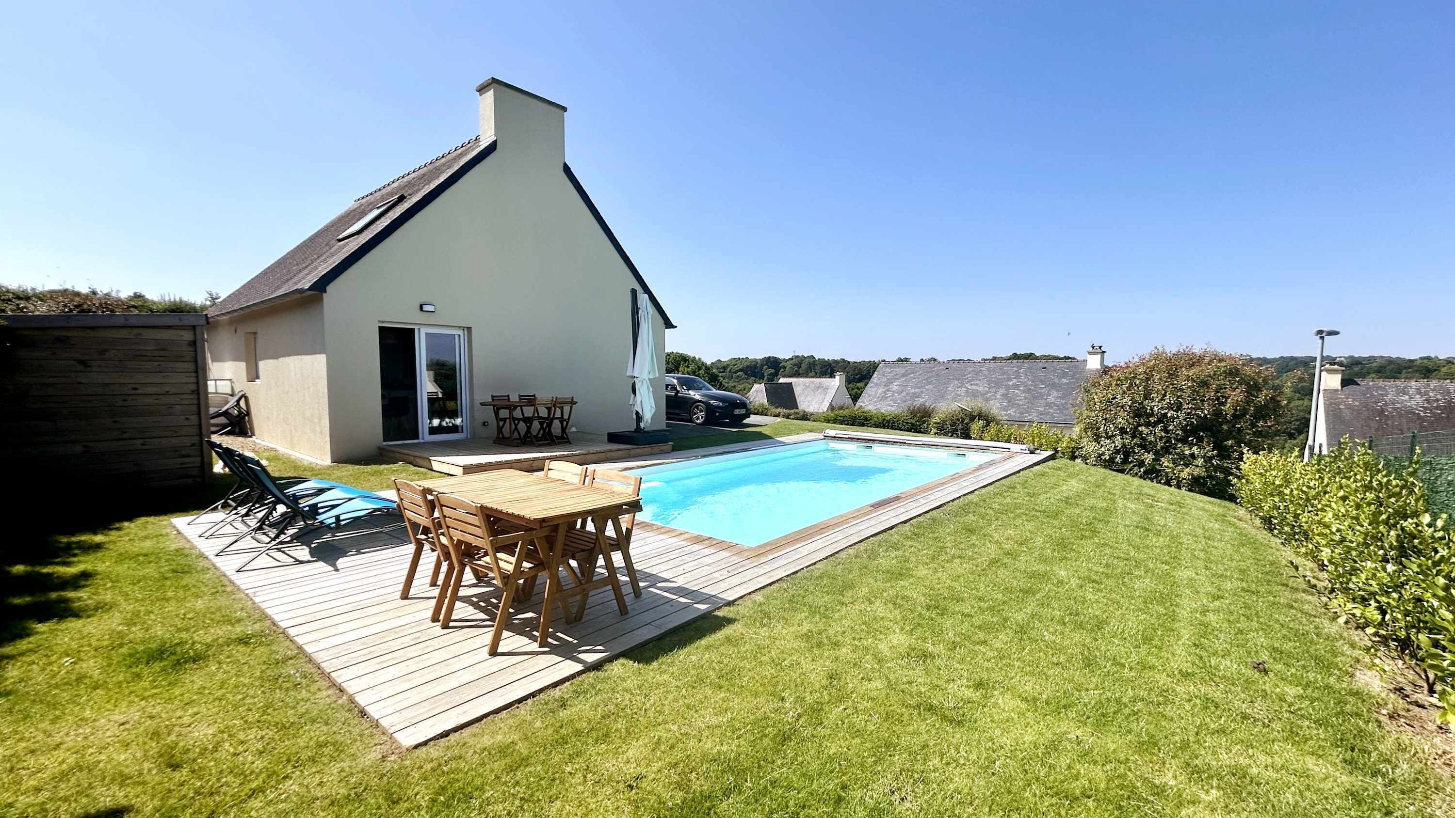 A house with a swimming pool, a deck with outdoor furniture, and a grassy yard.
