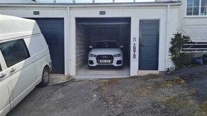 A white van parked outside a building with a garage door. - Boatman's Cottage Mousehole- Sleeps 4 -Garage (Mousehole)