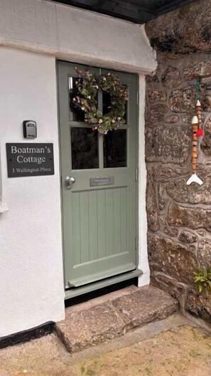 A cottage with a green door, a sign reading 'Boatman's Cottage,' and a stone wall. - Boatman's Cottage Mousehole- Sleeps 4 -Garage (Mousehole)