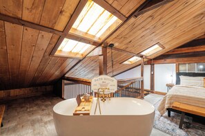 A room with a large bathtub, wooden beams, and skylights. - Entire Farm for 23 | Hot Tub, Sauna, 15 Min to AVL (Asheville)