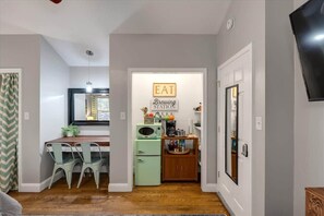 Cocina compacta con comedor, refrigerador de estilo vintage y un letrero que dice "BREWING STATION".