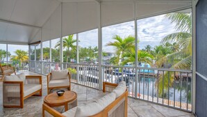 Ein geräumiger Balkon mit Blick auf eine Marina, ausgestattet mit Korbstühlen und einem runden Holztisch.
