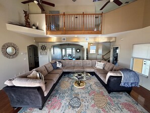 A spacious living area with a large sectional sofa, a coffee table, and a patterned rug.