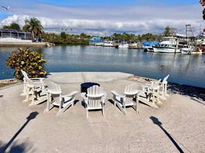 A marina with boats, a concrete seating area with chairs, and a small bush.