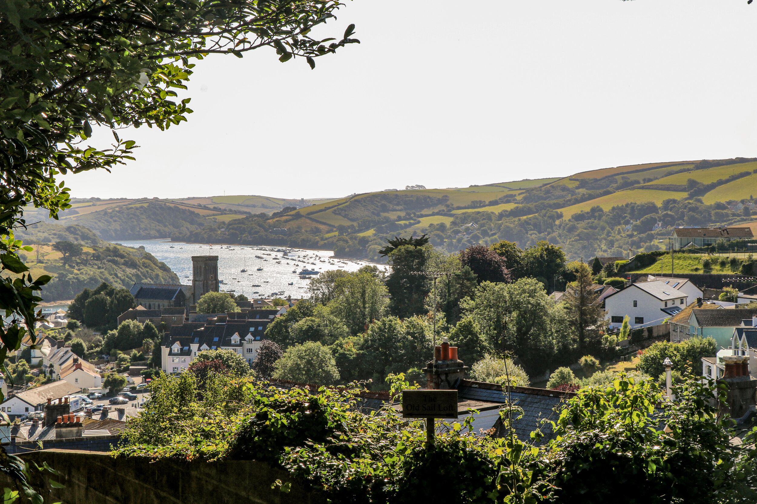 A coastal town with a prominent tower, lush greenery, and a view of the sea.