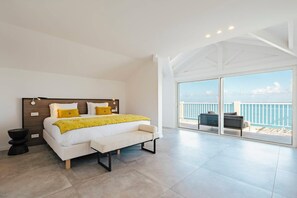 A modern bedroom with a large bed, a bench, and a balcony with a view of the sea. - Amazing ocean front 6-bedroom villa in Grand-Case Saint-Martin (Grand-Case)