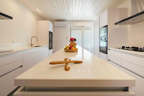A modern kitchen with a central island, white cabinetry, and a decorative fruit bowl. - Amazing ocean front 6-bedroom villa in Grand-Case Saint-Martin (Grand-Case)