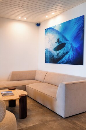 A modern living room with a beige sofa, a round wooden coffee table, and a large abstract painting on the wall. - Amazing ocean front 6-bedroom villa in Grand-Case Saint-Martin (Grand-Case)