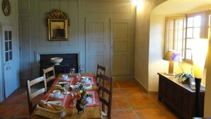 A dining room with a wooden table set for four, a fireplace, and a mirror above it. - Bienvenue à la Maison Forte de Chabanolles - Un lieu singulier et authentique (Retournac)