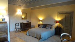 A bedroom with a bed, bedside tables, a dresser, a chair, and a mirror. - Bienvenue à la Maison Forte de Chabanolles - Un lieu singulier et authentique (Retournac)