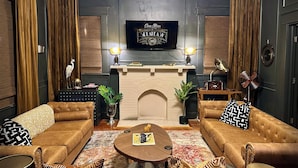 Una sala de estar acogedora con chimenea, dos sofás, una mesita de centro y un televisor montado en la pared.