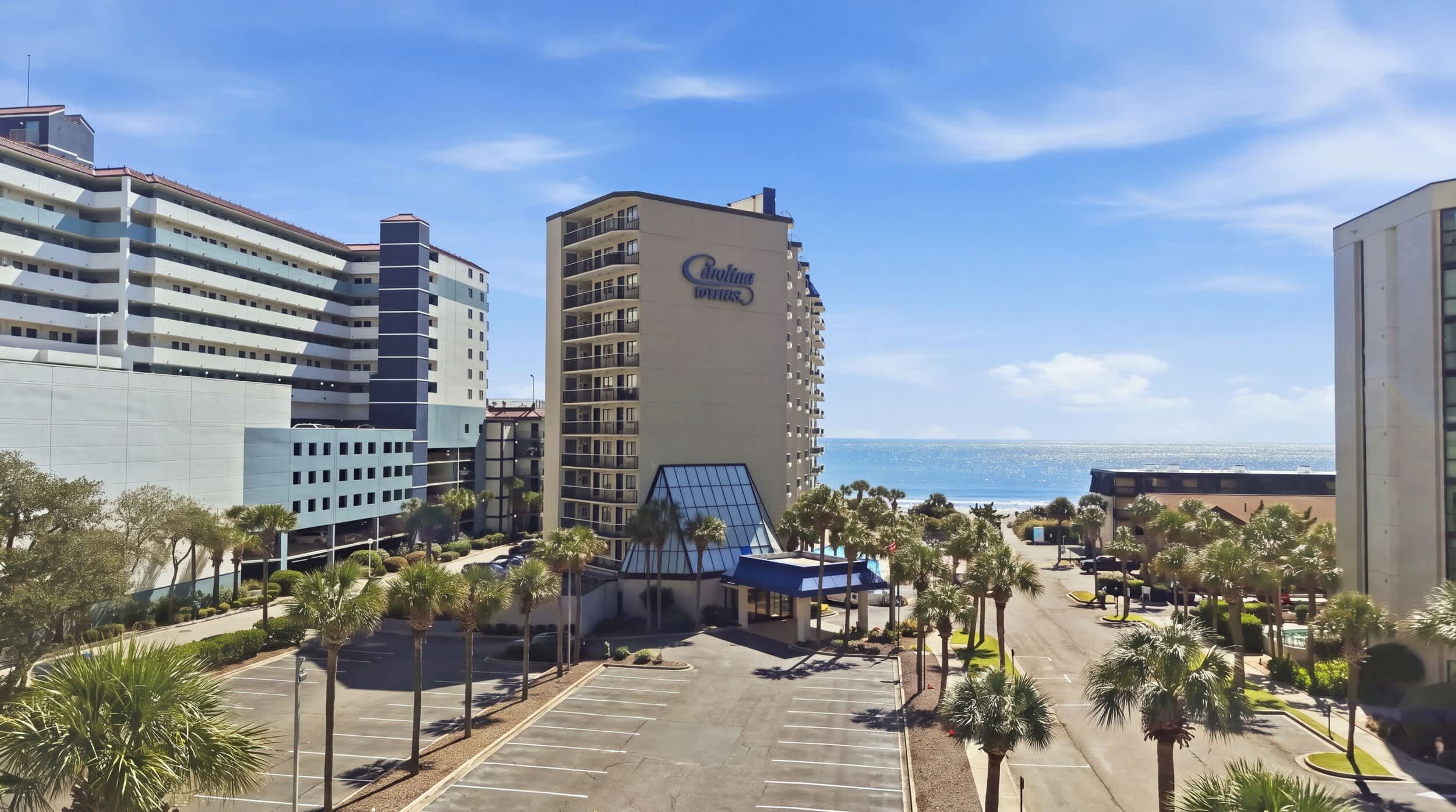 A hotel with a prominent 'Caribbean' sign, a parking lot, and a view of the ocean.