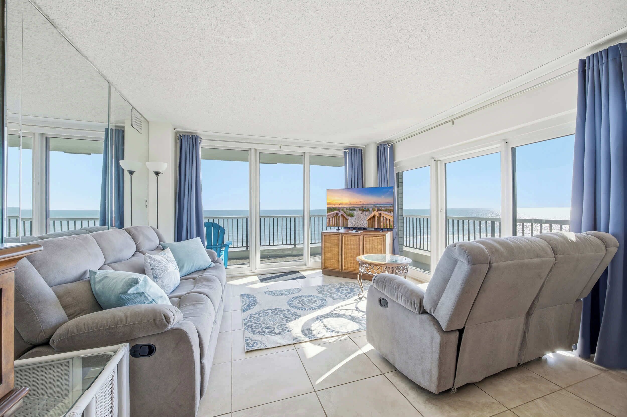 A spacious balcony with a sofa and armchair, a small table, and a TV.
