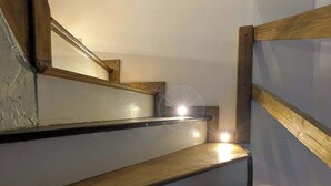 Una escalera de madera con barandilla que conduce a una plataforma con una fuente de luz.