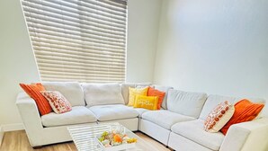 Una sala moderna con un sofá modular, una mesa de centro de cristal y suelo de madera.