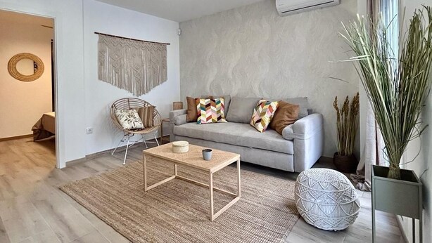 A modern living room with a grey sofa, a woven coffee table, and a rattan chair. - Baélia Casa Sabina (Alicante)