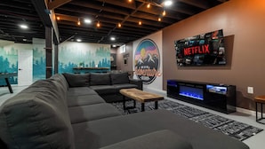Ein modernes Wohnzimmer mit einem Ecksofa, einem Couchtisch, einem Kamin und einem an der Wand befestigten Fernseher.