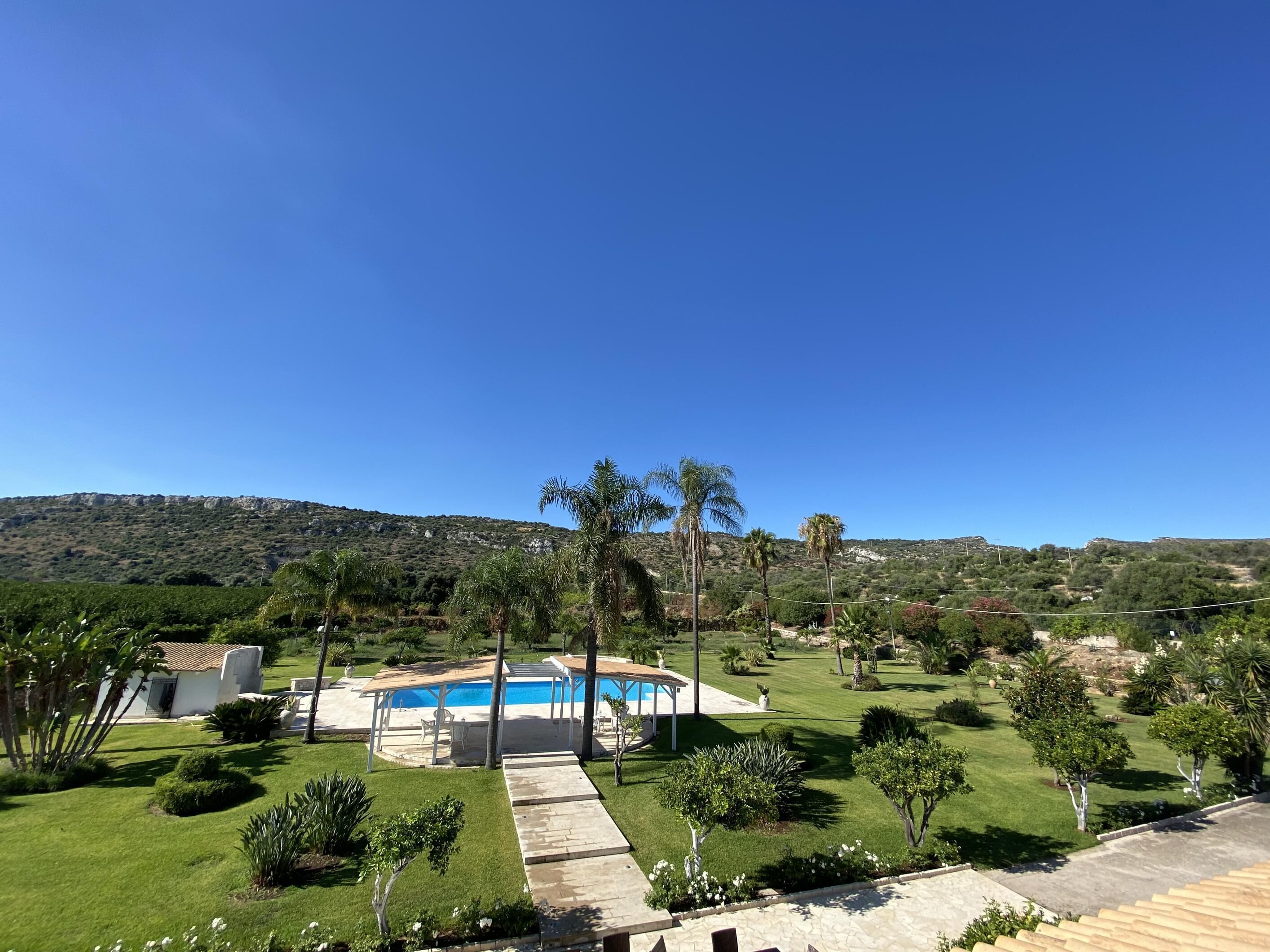 A residential property with a swimming pool, a covered patio, and a well-maintained lawn.