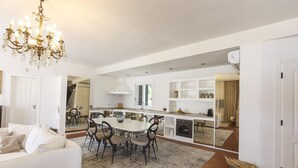 Een moderne keuken met een centraal eiland, witte kasten en een kroonluchter.