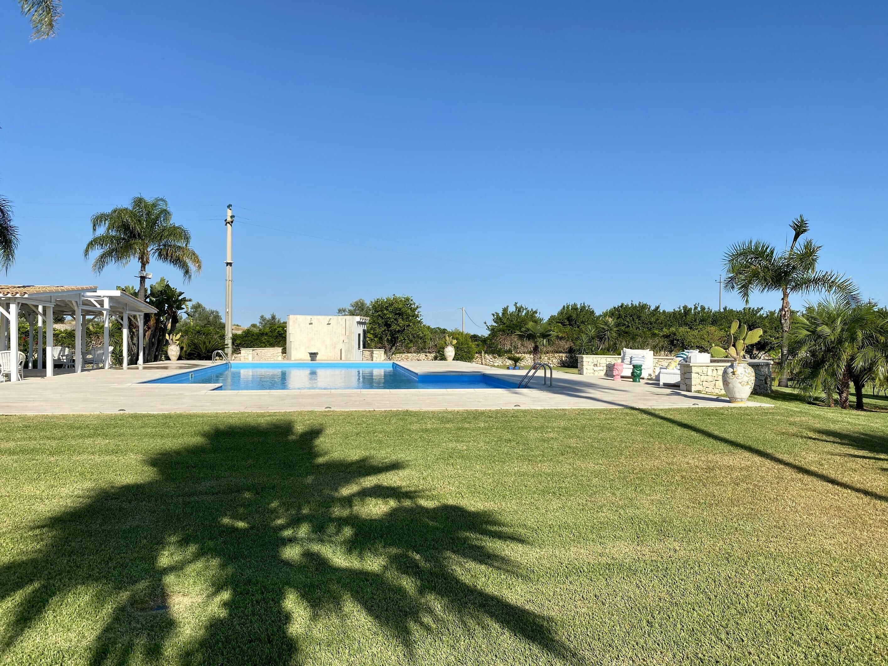 Une piscine avec un gazebo blanc et des palmiers en arrière-plan.
