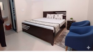 Un dormitorio con cama, mesita de noche y una silla azul.