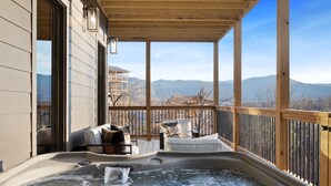 Een hottub op een houten terras met uitzicht op bergen.