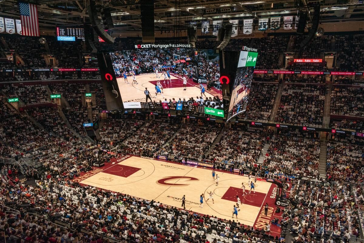 A basketball game in a large indoor arena with multiple screens displaying the game.
