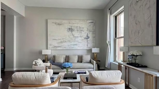 A modern living room with a large abstract painting, a sofa set, a coffee table, and a dining area with a wooden table.