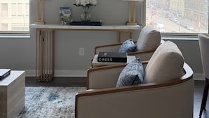 A modern living room with a large abstract painting, a console table with a vase of flowers, and a chess set.