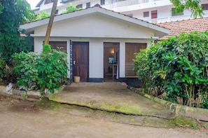 A white building with a tiled roof, a wooden door, and a small porch area.