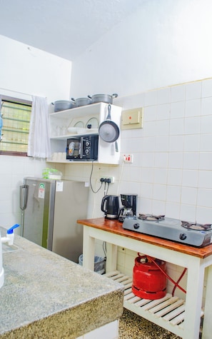 A compact kitchen with a refrigerator, a stove, and a coffee maker.